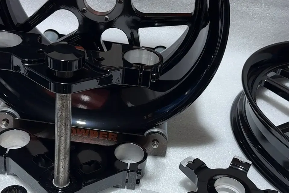Triple clamps in gloss black, in front of a wheel